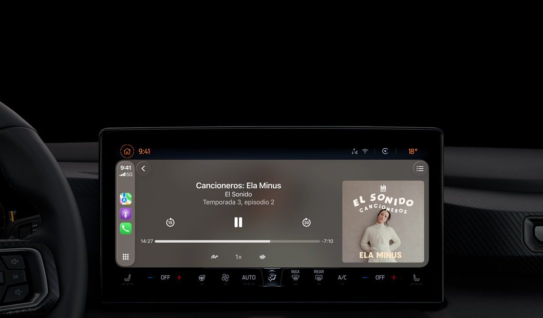 Interior de un carro, la pantalla de la consola central muestra Apple Podcasts reproduciéndose a través de CarPlay con el podcast "Cancioneros: Ela Minus" de El Sonido, aparecen los controles de reproducción para retroceder, pausar y avanzar.