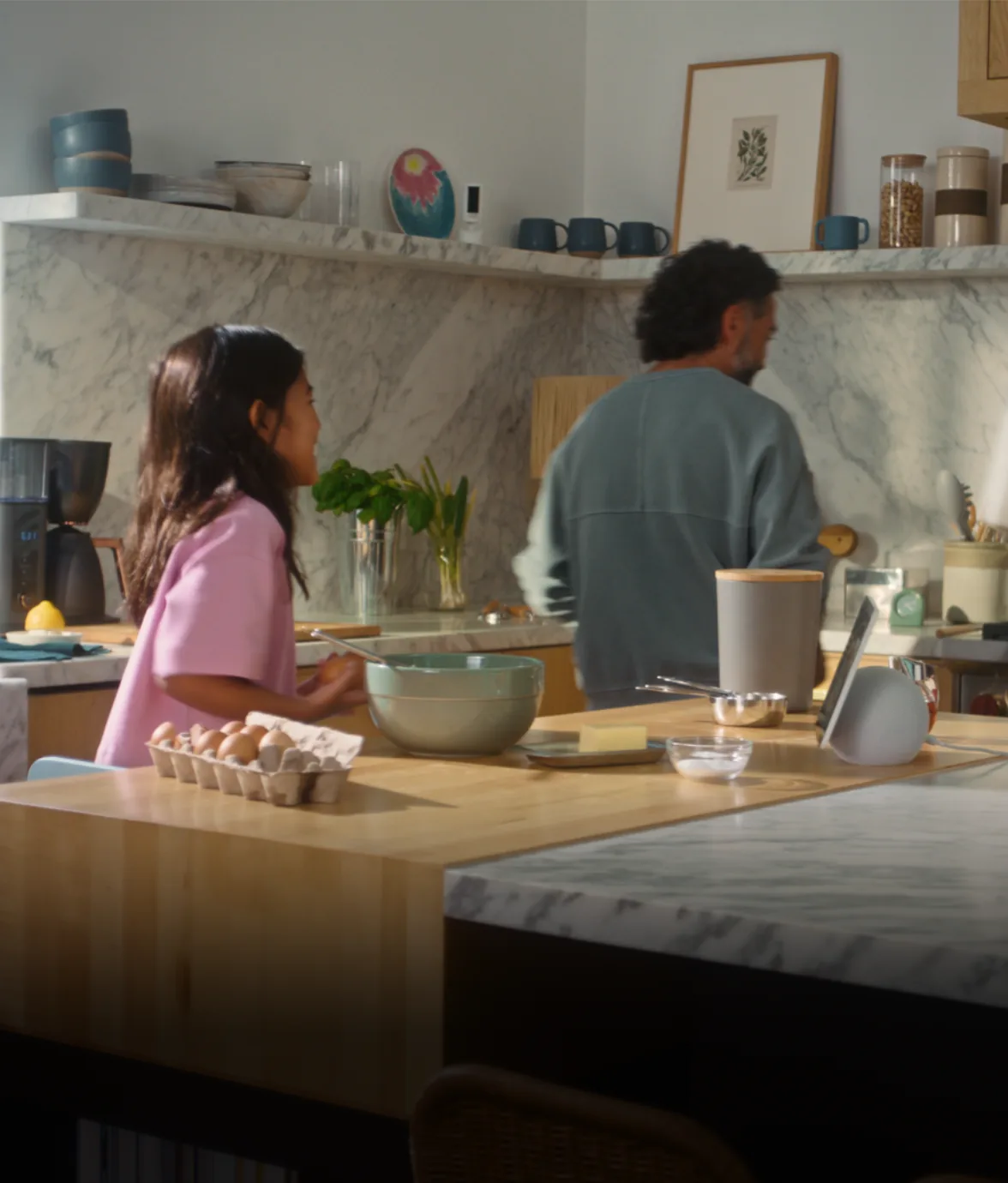 Una niña y un señor cocinan; el Echo Show 11 está en el mesón.