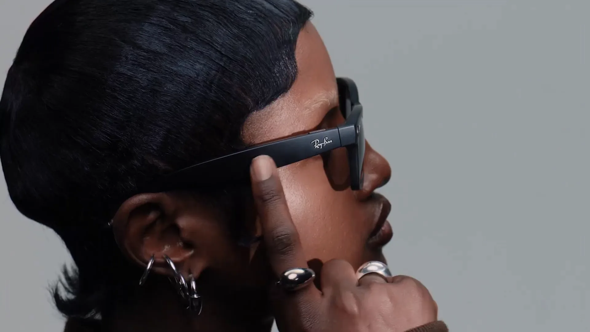 Una mujer con las Ray-Ban Meta Wayfarer negro mate se toca la varilla, de perfil.