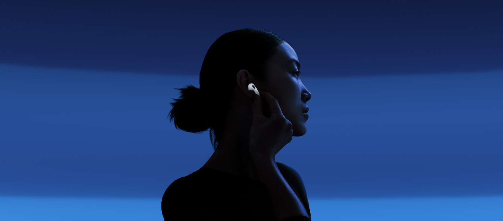 Una persona toca la parte inferior de unos AirPods 5 para habilitar la Cancelación Activa de Ruido