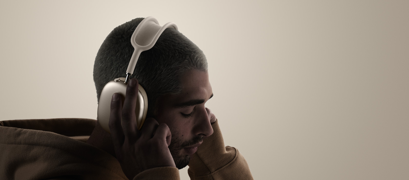 Una persona con unos AirPods Max 2 puestos, parte lateral, tocando las almohadillas