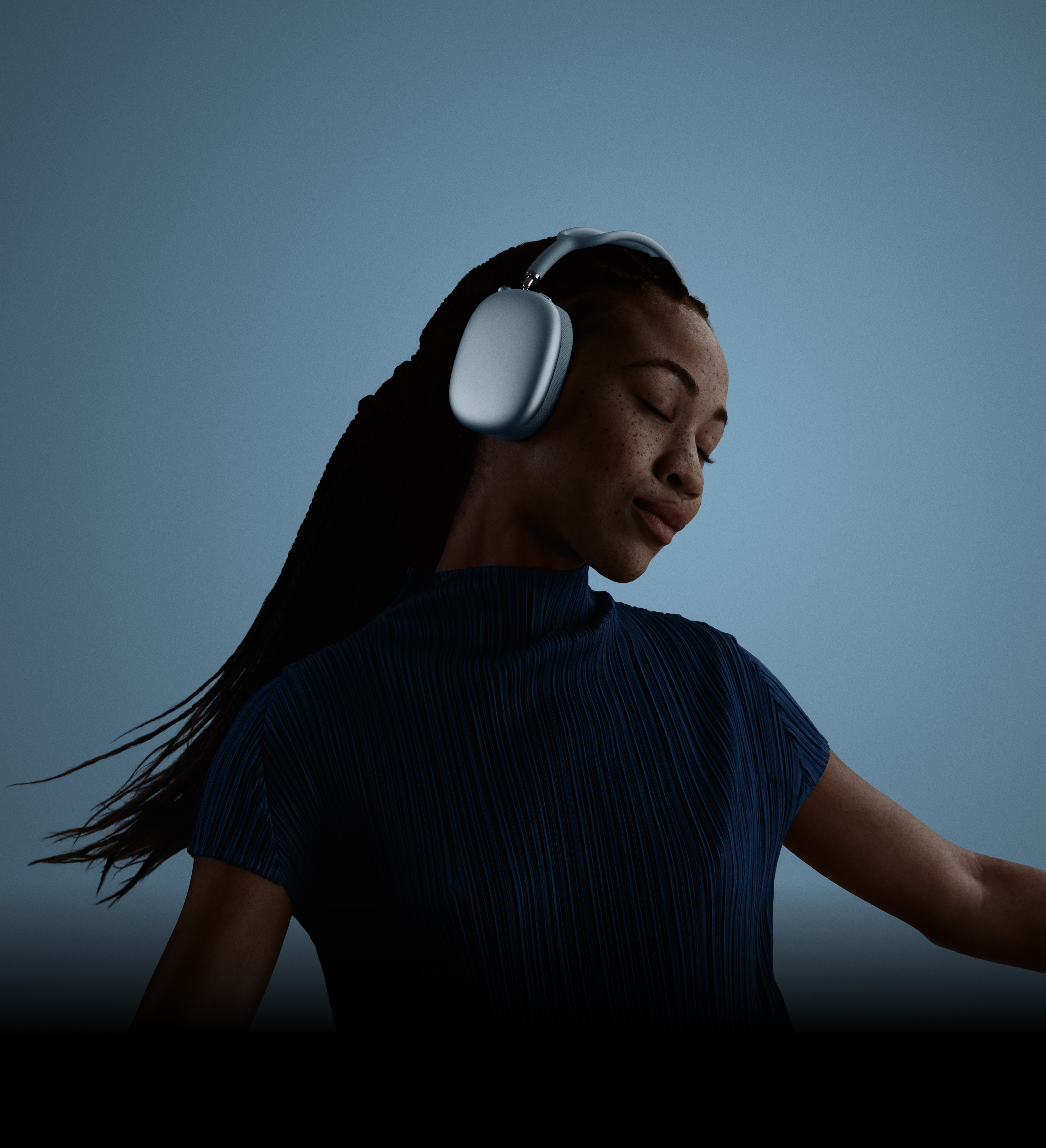 Perfil de una persona con los ojos cerrados y la cabeza inclinada usando unos AirPods Max 2 en color azul.