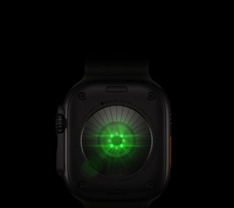 Parte posterior de un Apple Watch Ultra 4, caja de titanio, color negro, varios sensores redondos con luces LED verdes y brillantes, parte lateral izquierda, Digital Crown, botón lateral en relieve