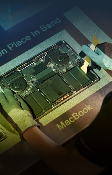 Unas manos con guantes desarman una MacBook, se ven los componentes internos