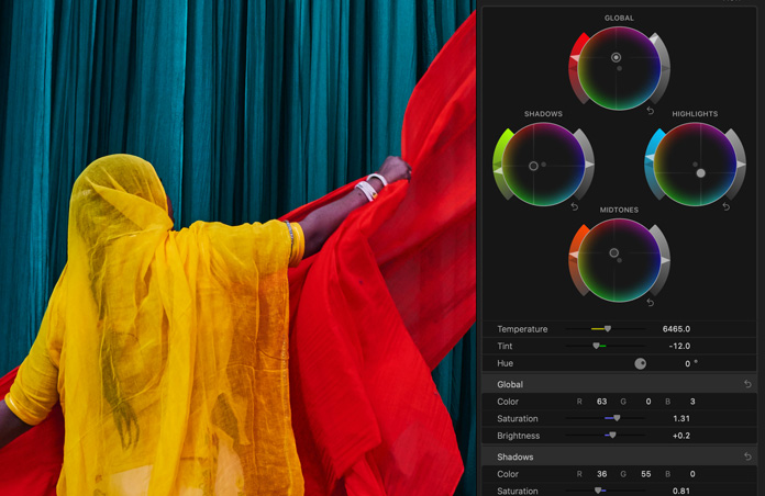 Pantalla que muestra a una mujer con un sari amarillo brillante y pañuelos rojos sobre un fondo azul, demostración de las herramientas de corrección de color
