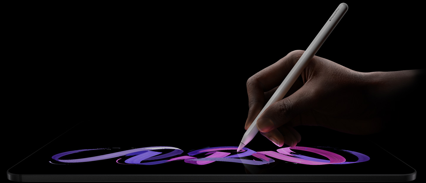 Un iPad Pro, parte frontal, posición horizontal, parte lateral, color negro espacial, una mano sostiene un Apple Pencil Pro, color blanco, y dibuja un diseño abstracto en morado y rosa sobre la pantalla