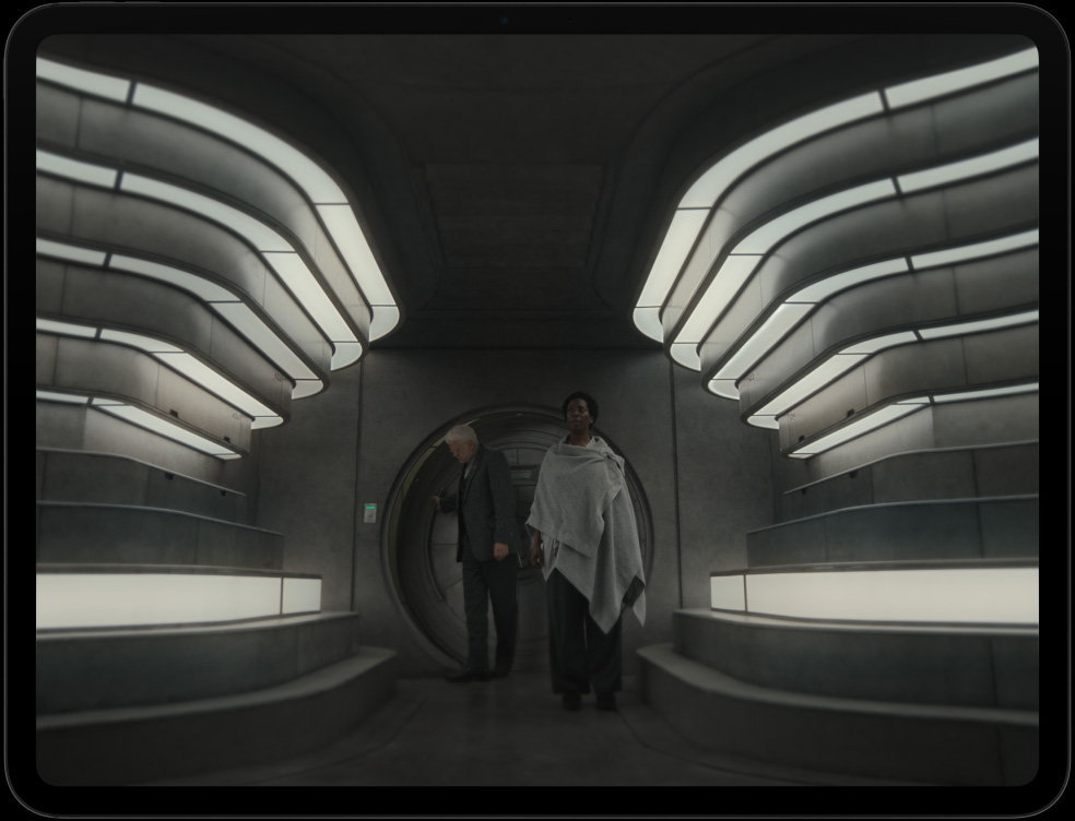 iPad Pro, la pantalla muestra una imagen de dos personas entrando a un espacio interior futurista en la serie Silo de Apple TV+.