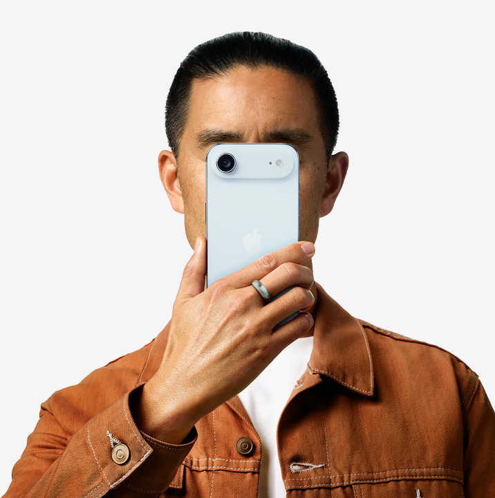 Una persona sostiene un iPhone Air en acabado azul cielo frente su cara mostrando la parte posterior y el sistema de dos cámaras en la esquina superior izquierda