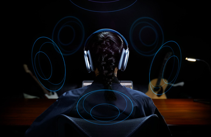 Vista posterior de la cabeza de una persona que usa unos AirPods Max de Apple y dibujos alrededor de su cabeza que indican que está escuchando Audio Espacial