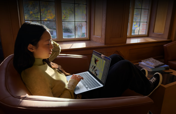 Una persona sentada en una silla usa una MacBook Air