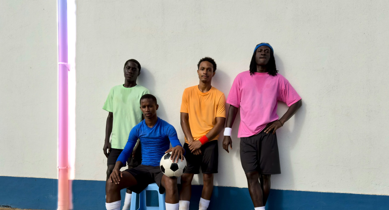 Uso de la herramienta Borrador para eliminar una tubería de una foto de jugadores de fútbol que posan contra una pared