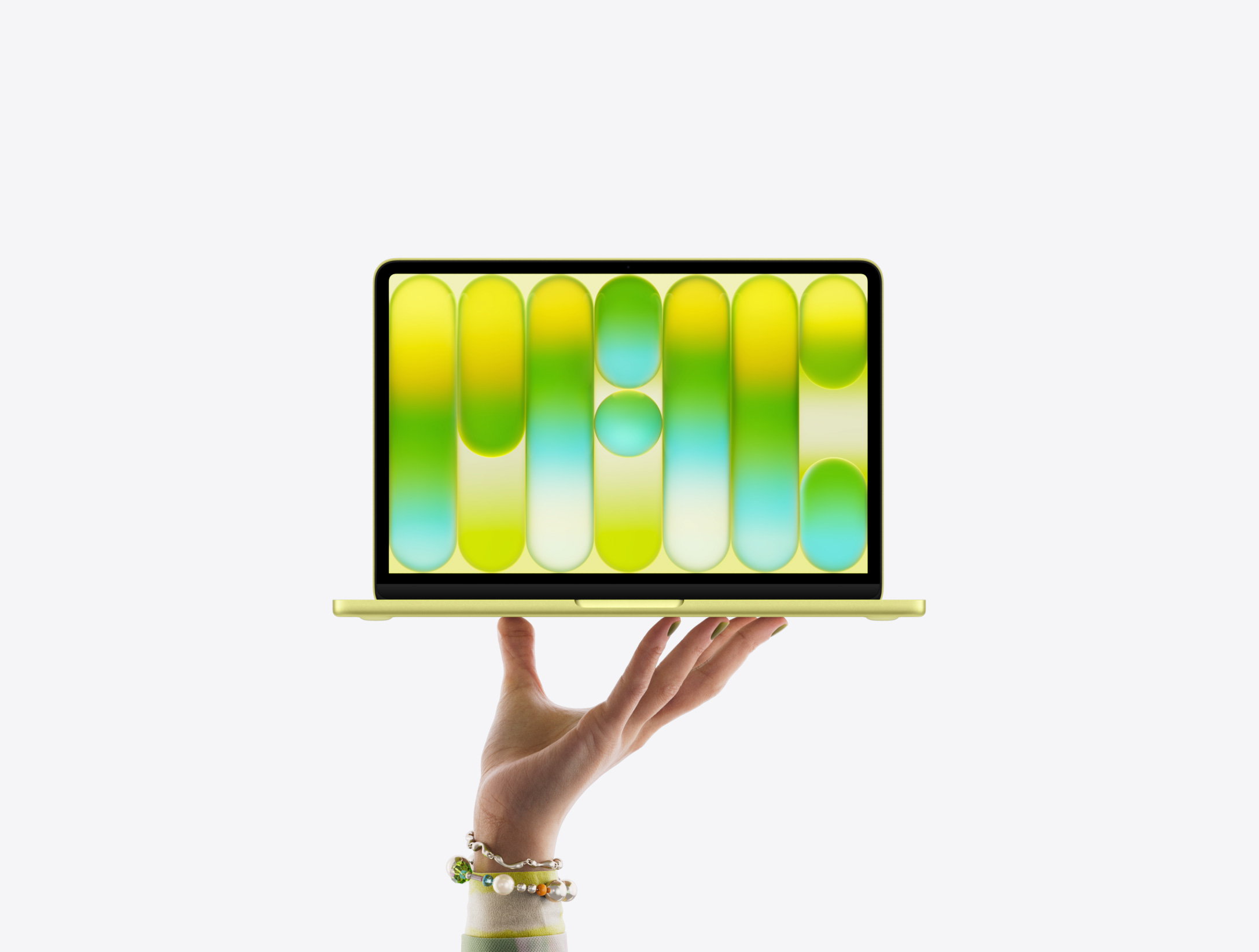 Una mano sostiene en la punta de los dedos una MacBook Neo en color amarillo cítrico, la pantalla muestra un patrón abstracto y colorido