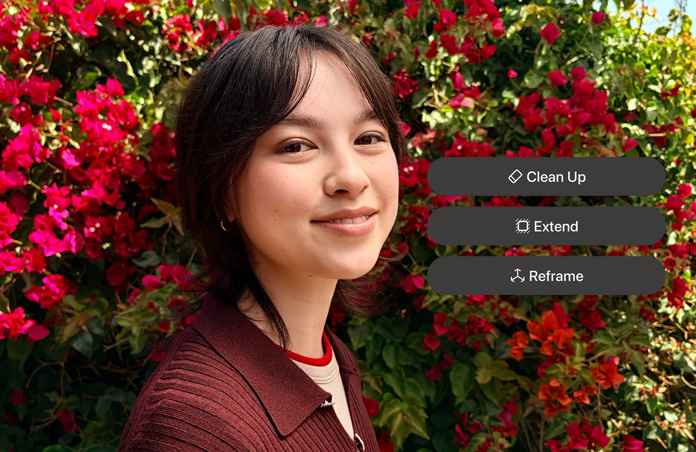 Foto de una persona sonriente de pelo castaño, vistiendo un suéter café, rodeada de flores rojas, demostración de edición de fotos con IA con las opciones Borrador, Ampliar y Reencuadrar en la foto