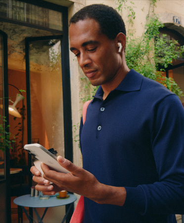 Una persona en la calle de una ciudad ve su iPhone, con una conexión Wi-Fi que se mantiene estable mientras alterna entre diferentes redes