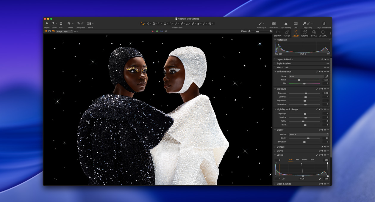Una persona vestida de negro de pie en ángulo junto a una persona vestida de blanco para mostrar el brillo y contraste que alcanza el monitor Studio Display XDR